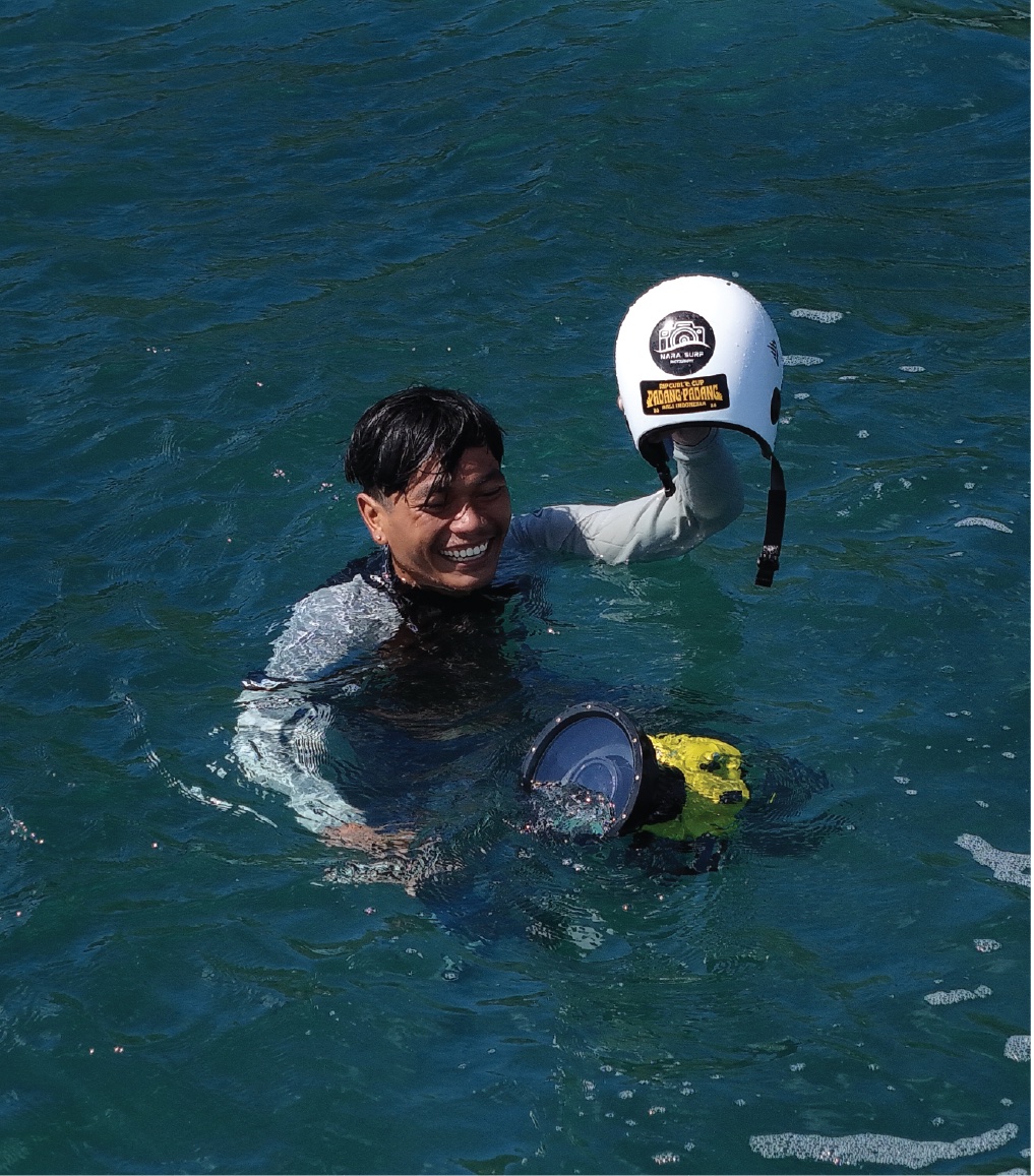Arik in the water holding up a helmet